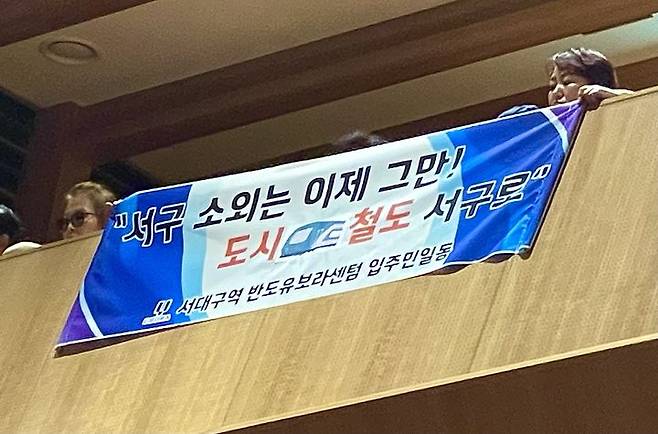 [대구=뉴시스] 정재익 기자 = 26일 대구 북구 iM뱅크 제2본점 대강당에서 열린 '대구도시철도망 구축계획 주민 수렴 공청회'에서 일부 서구 주민들이 5호선 예상 노선도를 항의하는 현수막을 걸었다. 2025.06.26. jjikk@newsis.com *재판매 및 DB 금지
