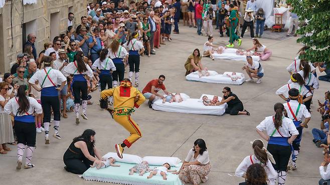 지난 22일 스페인 부르고스 인근 카스트리요 데 무르시아 마을에서 열린 '엘 살토 델 콜라초'(El salto del Colacho 악마의 점프) 페스티벌에서 악마로 분장한 '콜라초'가 매트리스 위에 누워 있는 아기들 위로 뛰어오르고 있다./AFP 연합뉴스