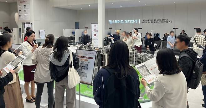 은평구 ‘힐스테이트 메디알레’ 견본주택 내부 모형 앞에서 방문객이 도우미의 설명을 듣고 있다. 사진=현대건설