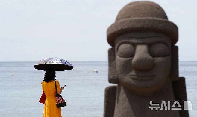 [제주=뉴시스] 우장호 기자 = 19일 오후 제주시 이호해수욕장에서 한 관광객이 양산으로 뜨거운 태양을 피하고 있다. 올해 조기 개장하는 도내 해수욕장은 함덕·이호·협재·금능·월정·곽지를 비롯해 삼양·김녕·화순·표선 등 총 10곳(24일)이며, 신양과 중문 해수욕장은 26일과 30일 각각 개장한다. 2025.06.19. woo1223@newsis.com