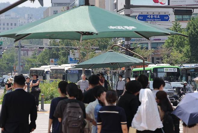 지난 23일 서울 광화문에서 출근길 시민들이 대형 그늘막 아래 신호를 기다리고 있다. 지방 취업은 꺼리면서도 수도권 일자리에 몰리는 청년들이 많아지며, 서울 도심의 출퇴근 혼잡은 여전하다. 연합뉴스