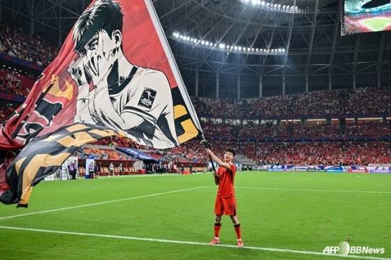 왕위동이 중국 충칭의 롱싱 축구 경기장에서 열린 2026 국제축구연맹(FIFA) 북중미월드컵 3차 예선 최종전 바레인과 경기가 끝난 뒤 서포터가 선물한 깃발을 펄럭이고 있다. /AFPBBNews=뉴스1