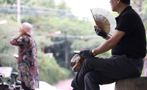 더운 날씨 속 대구 달서구 성당못 나무 그늘에서 한 시민이 부채질하며 더위를 식히고 있다. [사진=연합뉴스]