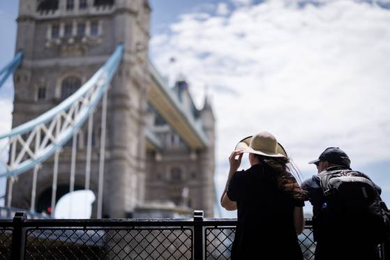 지난 27일(현지시간) 영국 런던의 여름 날씨에 사람들이 타워 브리지 옆에서 쉬고 있다. 기상청은 앞으로 며칠간 기온이 섭씨 34~35도까지 오를 것으로 예상하고 있다. EPA=연합뉴스