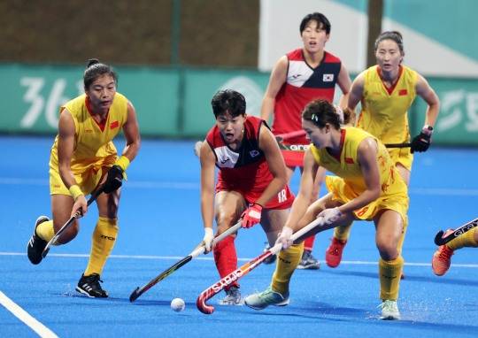 국제대회에서 여자 하키 선수들이 스쿱 동작으로 볼을 다루는 모습.