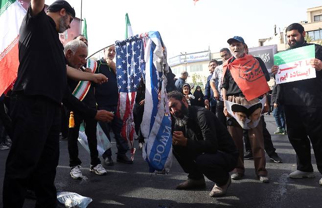 28일 이스라엘의 공습으로 숨진 핵 과학자 등의 장례식에서 이란 주민들이 이스라엘과 이란의 국기를 태우고 있다. 연합뉴스