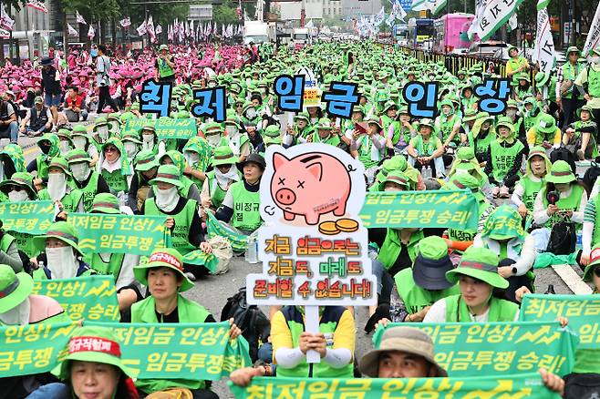 민주노총 산하 단체 회원들이 28일 '최저임금 인상, 노동기본권 쟁취 결의대회'에 참석해 피켓을 흔들고 있다. 연합뉴스