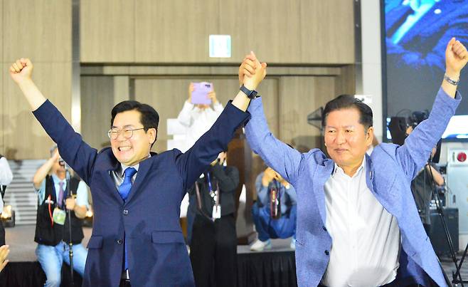 더불어민주당 당대표 선거에 출마한 박찬대(왼쪽), 정청래 의원이 29일 충북 청주시에서 열린 더민주전국혁신회의 전국 대회에 참석해 손을 들어 인사하고 있다. 두 의원은 이재명 대통령의 친위 조직이라는 혁신회의 참석자들 앞에서 명심(明心) 얻기 경쟁을 벌였다./뉴시스