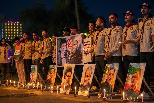 28일(현지시각) 바그다드 주재 이란 대사관 앞에서 열린 추모 행사에서 레바논 헤즈볼라와 이란 혁명수비대(IRGC) 사망 지도자들의 사진 뒤에 정찰대(스카우트) 단원들이 서 있다. 이번 행사는 최근 이스라엘의 공습으로 사망한 혁명수비대 요원들과 과학자들을 추모하기 위해 열렸다. 바그다드/AFP 연합뉴스