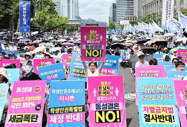14일 서울 중구 서울시청 인근에서 열린 '동성애퀴어축제반대 국민대회'의 참가자들이 동성결혼과 차별금지법, 학생인권특별법 제정 등에 반대하는 피켓을 들고 앉아 있다. 뉴스1