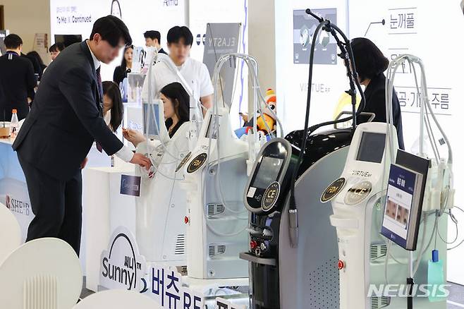 [서울=뉴시스] 황준선 기자 = 14일 서울 서초구 aT센터에서 열린 2024 미용의료기기 박람회를 찾은 관람객들이 레이저 미용 의료기기를 살펴보고 있다. 2024.04.14. hwang@newsis.com