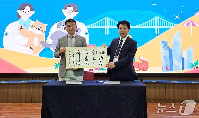 이영락 부산시수의사회 회장(오른쪽)이 28일 양기청 상하이동물병원협회 회장과 협약을 맺고 기념품을 교환하고 있다. ⓒ 뉴스1