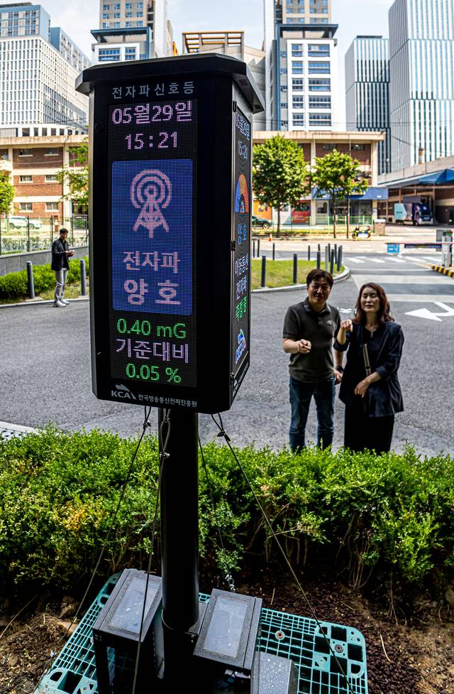 시민들이 지난 5월 29일 서울 금천구 SK브로드밴드 가산데이터센터 입구에 세워진 전자파 신호등을 살펴보고 있다. 전자파 신호등은 한국방송통신전파진흥원(KCA)이 자체 개발한 IoT(사물인터넷) 기반 이동통신 기지국 전자파 모니터링 측정기와 연동한 서비스로, 실시간 전자파 측정 정보를 기지국 인근 주민들에게 3색의 신호등으로 알기 쉽게 제공한다, 박동욱기자 fufus@