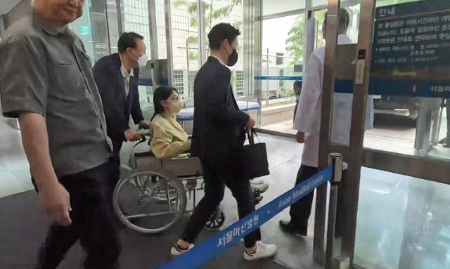 김건희 여사가 27일 서울 송파구 서울아산병원에서 윤석열 전 대통령이 미는 휠체어에 탄 채 퇴원하고 있다. 연합뉴스