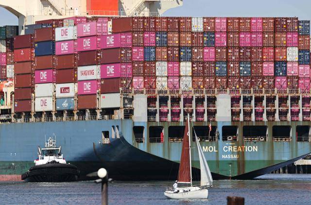 25일 수입품을 실은 대형 선적이 미국 로스앤젤레스항에서 컨테이너선에 적재된 컨테이너들을 지나가고 있다. LA=AFP 연합뉴스