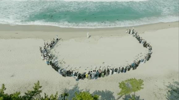 배우 유준상이 연출한 영화 ‘청명과 곡우 사이’의 한 장면. 박정자(가운데)가 그가 출연한 작품의 제목이 적힌 만장을 든 150명의 지인들에게 둘러싸여 있다. 쥬네스엔터테인먼트 제공