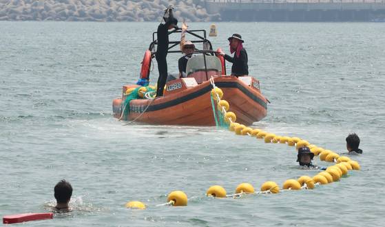 지난달 27일 오후 부산 수영구 광안리 해변에서 100m쯤 떨어진 수상 구역에서 구청 관계자가 해파리 차단 그물망을 설치하고 있다. 수영구는 9월까지 차단 그물망을 운영할 계획이다. 〈사진=연합뉴스〉