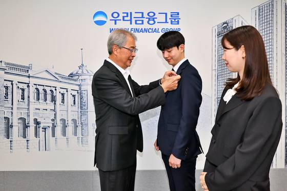 임종룡 우리금융그룹 회장이 1일 서울 중구 우리금융지주 본사에서 그룹의 새 가족이 된 동양생명·ABL생명 직원에게 디지털 선도의 의미가 담긴 그룹 보조 휘장을 달아주고 있다. 사진 우리금융