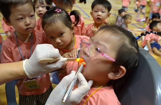 Children receive a dental checkup during a free dental clinic event at a school in Daejeon on June 12. [KIM SUNG-TAE]