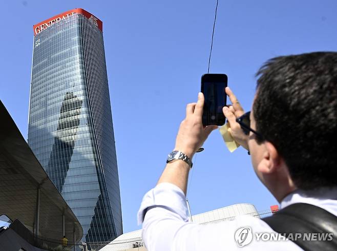 주저앉은 제네랄리 간판을 휴대전화로 촬영하는 한 남성 [EPA 연합뉴스. 재판매 및 DB 금지]