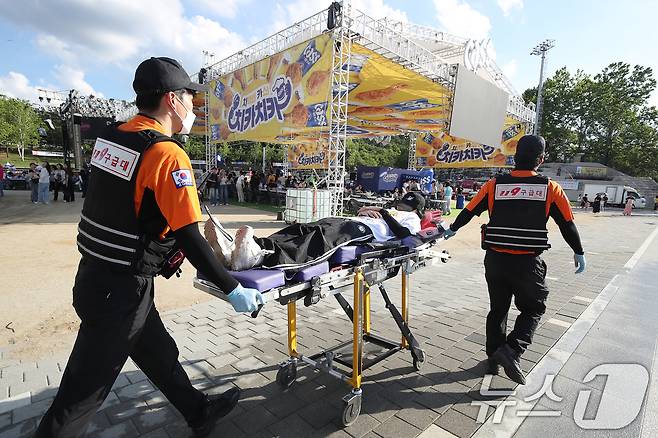대구에 폭염경보가 닷새째 이어진 2일 오후 달서구 두류공원에서 '2025 대구치맥페스티벌' 개막식을 준비하던 한 20대 여성 스태프가 탈수증상과 어지러움 등을 호소하다 행사장에 대기하던 119구급대의 들것에 실려 가고 있다. 2025.7.2/뉴스1 ⓒ News1 공정식 기자