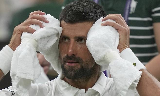 노바크 조코비치가 2일(한국시각) 영국 런던에서 열린 윔블던 남자 단식 1라운드 알렉상드르 뮐러(프랑스)와 경기가 끝난 뒤 차가운 수건을 머리에 두르고 있다. 런던/AP 연합뉴스