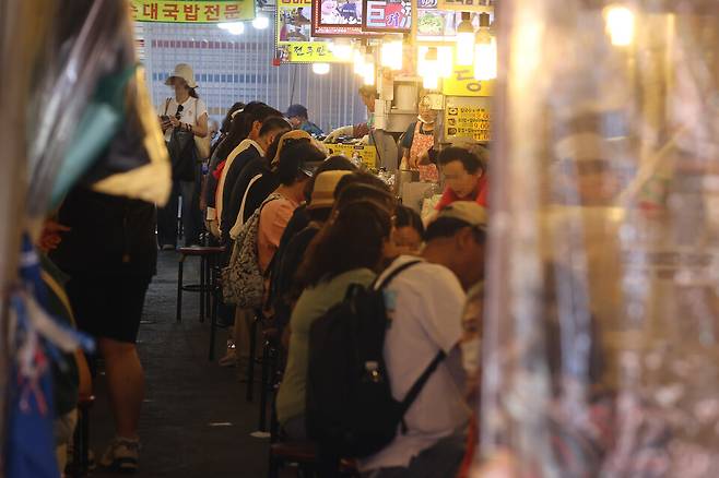 정부가 2차 추가경정예산안으로 전 국민에게 15만&sim;52만원씩 민생회복 소비쿠폰을 지급하기로 나선 가운데 실제 소비 진작 효과가 나타날지 이목이 쏠린다. 사진은 지난 22일 서울 남대문시장에서 시민들이 상점에서 식사를 하는 모습ⓒ 연합뉴스