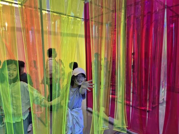 김포아트빌리지 내 한옥마을을 찾은 한 학생이 다채로운 빛과 색으로 꾸며진 기획전시 ‘비밀의 정원’을 관람하며 손을 흔들고 있다. /김포문화재단 제공
