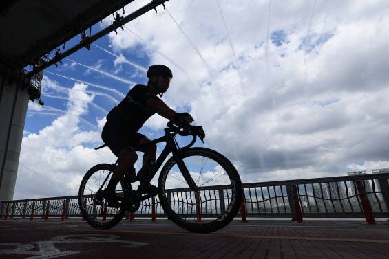 비가 그친 뒤 서울 한낮 기온이 31도까지 치솟으며 더운 날씨를 보인 1일 서울 서초구 잠수교에서 한 시민이 무지개분수 아래로 자전거를 타고 있다.(사진=연합뉴스)