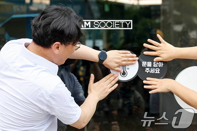 이원주 산업통상자원부 대변인이 2일 오후 서울 중구 명동 온드림 소사이어티에서 열린 '여름철 에너지절약 캠페인'에 참석해 출입문에 개문냉방 자제 스티커를 붙이고 있다. 2025.7.2/뉴스1 ⓒ News1 민경석 기자