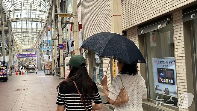3일 낮 최고기온 36도를 기록한 울산 중구의 젊음의거리에서 시민이 양산을 쓰고 지나가고 있다.2025.7.3/뉴스1 ⓒNews1 김지혜 기자