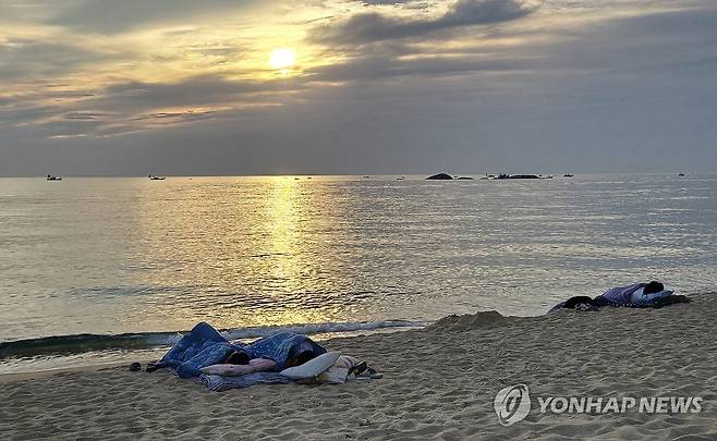 해변은 열대야 없어요 (강릉=연합뉴스) 유형재 기자 = 강원 동해안에 무더위가 계속되는 가운데 22일 새벽 강릉시 경포해변 백사장에서 시민들이 이불을 덮고 잠을 자고 있다. 강릉은 최근 이틀 연속 열대야가 발생한 바 있다. 2025.6.22 yoo21@yna.co.kr