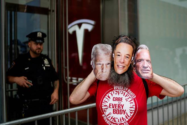 일론 머스크 테슬라 CEO의 가면을 쓴 한 사람이 테슬라 매장 앞에서 카메라를 바라보고 있다. (사진=로이터)