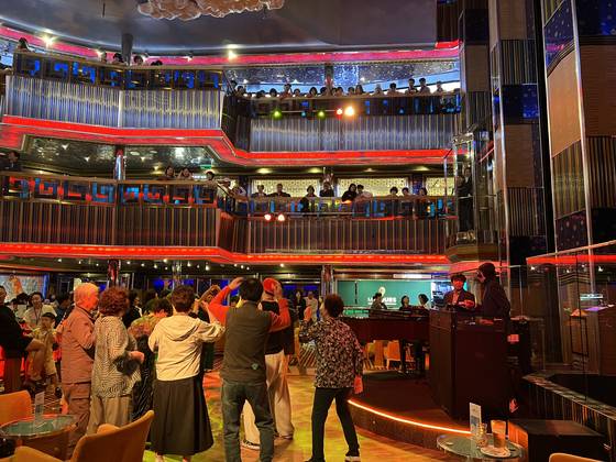 3층 메인홀에서 승객들이 춤추며 음악을 즐기고 있다.