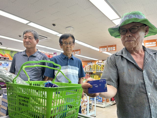 충남 논산 벌곡면에 사는 김영식씨(오른쪽)가 논산계룡농협 벌곡지점 하나로마트에서 장을 본 뒤 논산사랑상품권을 쓸 수 있는 카드를 내밀었지만 사용할 수 없었다.
