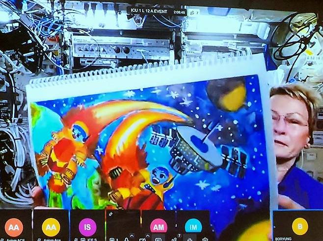 [서울=뉴시스] 이승주 기자=미국 우주비행사 페기 윗슨이 국제우주정거장에서 대한민국 초등학생의 그림을 소개하는 모습. 보령은 연세대학교 미래교육원 대강당에서 국제우주정거장(ISS)과 연결되는 'Humans In Space(HIS) Youth 수상작 우주정거장 발표 생중계' 행사를 개최했다.  2025.07.05. heyjude@newsis.com *재판매 및 DB 금지