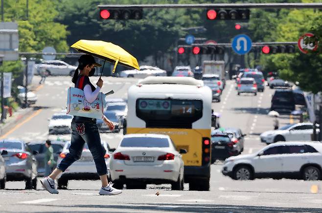 전국 대부분 지역에 폭염 특보가 발효된 지난 3일 광주 서구 치평동에서 한 시민이 강렬한 햇빛에 달구어져 아지랑이가 피어오르는 도로를 걷고 있다.  [연합]