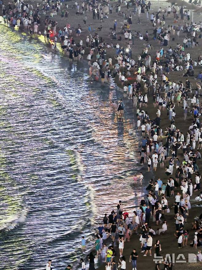 [부산=뉴시스] 하경민 기자 = 폭염특보와 열대야 현상으로 인해 밤낮으로 푹푹 찌는 더위가 이어진 5일 밤 부산 수영구 광안리해수욕장에서 시민과 관광객들이 더위를 식히고 있다. 2025.07.06. yulnetphoto@newsis.com