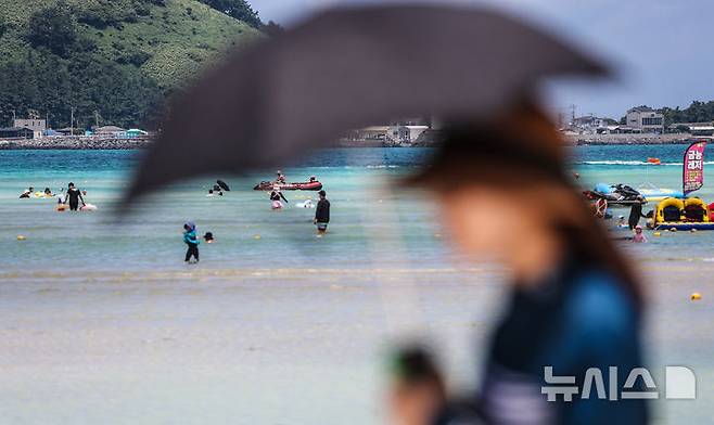 [제주=뉴시스] 우장호 기자 = 폭염의 기세가 수그러들지 않는 6일 오후 제주시 한림읍 금능해수욕장을 찾은 피서객들이 시원한 바닷물에 발을 담그며 더위를 식히고 있다. 2025.07.06. woo1223@newsis.com