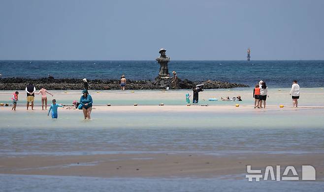 [제주=뉴시스] 우장호 기자 = 폭염의 기세가 수그러들지 않는 6일 오후 제주시 한림읍 금능해수욕장을 찾은 피서객들이 시원한 바닷물에 발을 담그며 더위를 식히고 있다. 2025.07.06. woo1223@newsis.com