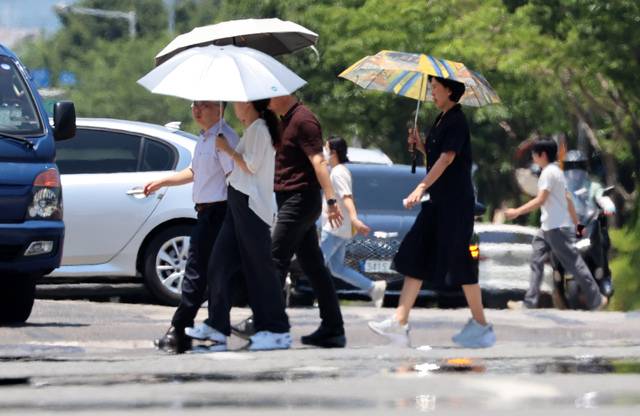 시민들이 강렬한 햇빛에 달궈져 아지랑이가 피어오르는 도로를 걷고 있다. 연합뉴스