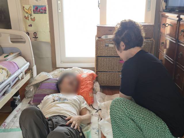 5년 전 중증 장애 진단을 받은 여동생과 치매를 겪는 어머니를 돌보는 이연희(52·가명) 씨가 좁은 거실에서 동생의 기저귀를 갈아주고 있다. 김지효 기자