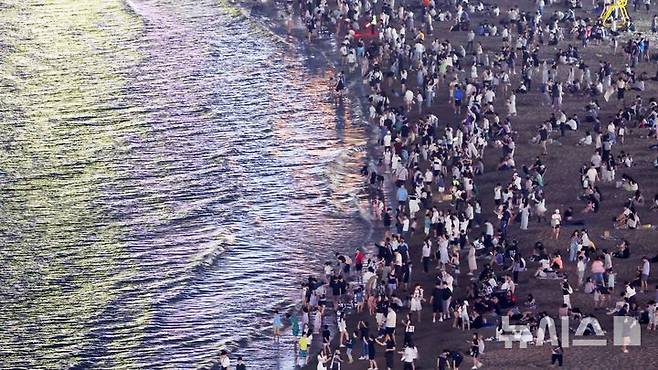 [부산=뉴시스] 하경민 기자 = 폭염특보와 열대야 현상으로 인해 밤낮으로 푹푹 찌는 더위가 이어진 5일 밤 부산 수영구 광안리해수욕장에서 시민과 관광객들이 더위를 식히고 있다. 2025.07.06. yulnetphoto@newsis.com
