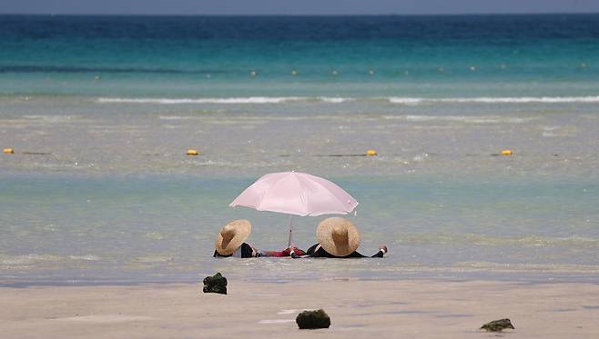 폭염의 기세가 수그러들지 않는 6일 오후 제주시 한림읍 금능해수욕장을 찾은 피서객들이 시원한 바닷물에 발을 담그며 더위를 식히고 있다. 뉴시스