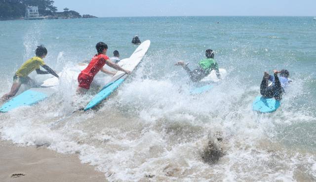 오는 14일부터 19일까지 부산 송정해수욕장 일대에서 ‘2025 송정 서프앤그루브(Surf& Groove) 페스티벌’이 열린다. 지난달 29일 송정해수욕장에서 열린 서핑대회에 참가한 선수들이 바다로 뛰어들고 있다. 이재찬 기자 chan@