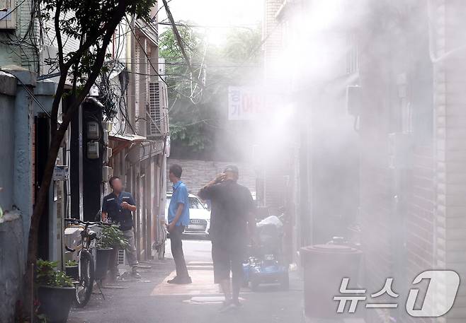 8일 오후 서울 용산구 동자동 쪽방촌에서 주민들이 쿨링포그 아래에서 더위를 피하고 있다. 이날 오후 2시쯤 서울 기온은 37.1도까지 오르면서 7월 상순 기온으론 역대 최고치를 기록했다. 2025.7.8/뉴스1 ⓒ News1 구윤성 기자