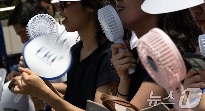 8일 오전 서울 중구 청계광장에서 열린 'K-바캉스 캠페인' 개회식 참석자들이 미니 선풍기와 부채로 더위를 식히고 있다. 한국경제인연합회는 여름 휴가철을 맞아 국내 관광 수요를 확대하고 침체된 지역경제에 활력을 불어넣기 위해 이번 행사를 기획했다고 밝혔다. 2025.7.8/뉴스1 ⓒ News1 이승배 기자