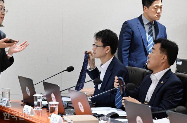 8일 대통령실에서 열린 국무회의에 참석한 배석자들이 복장이 노타이 차림이라는 사실을 뒤늦게 알고 넥타이를 풀고 있다. 왕태석 선임기자