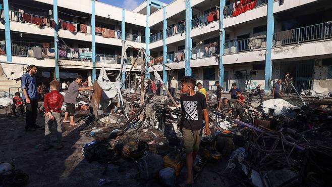 8일(현지시간) 가자지구 중부의 이스라엘 공습 현장 둘러보는 팔레스타인 피란민들