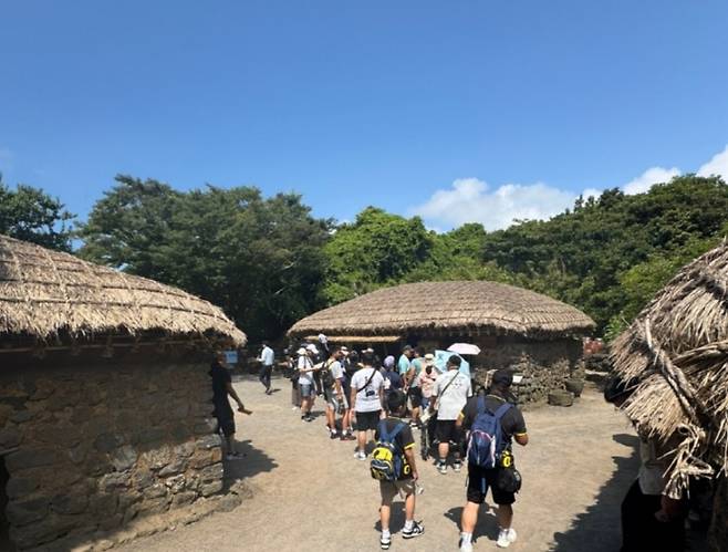 8일 전통 초가집 앞에서 대만 크루즈 단체 관광객들이 줄지어 이동 중이다.